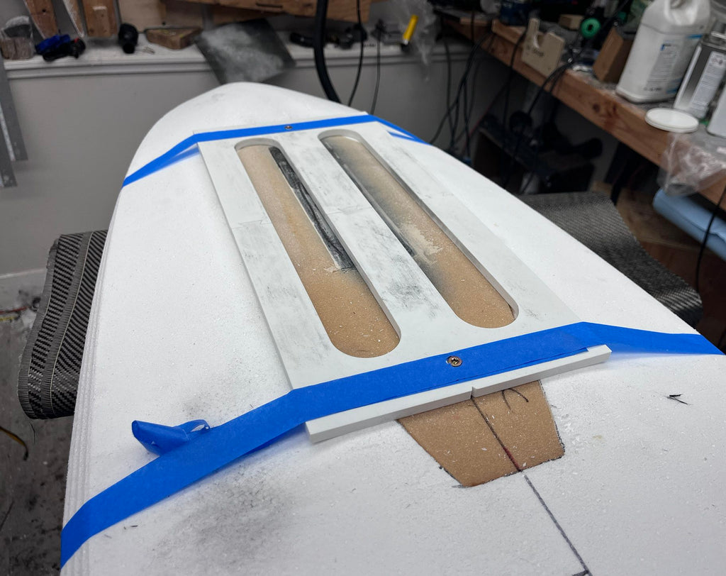Carbon track router jig taped to a board for routing track pockets